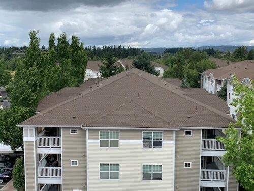 Exterior view of large residential building with completed roofing